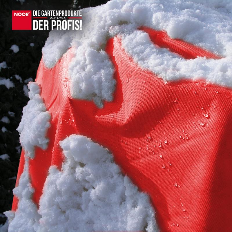 Mit buntem Winterschutzvlies eingepackte Sträucher als optischer Akzent im winterlichen Garten