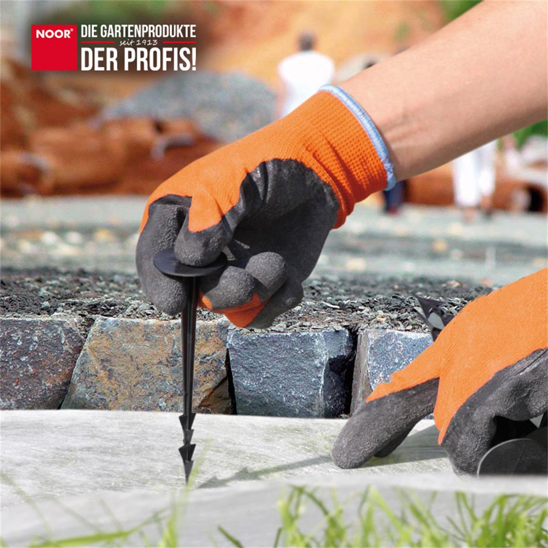 Fixierung eines schwarzen Unkrautvlieses mit Kunststoff-Erdankern zur Vorbereitung eines Gartenbeets