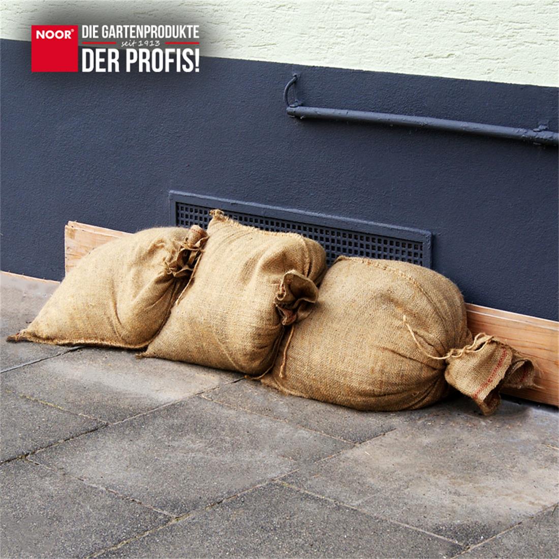 Gestapelte Jute-Sandsäcke als wirksame Barriere gegen Wasser bei Überflutungen und Starkregen