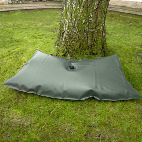 Großer, flach liegender dunkelgrüner FROGBAG Fatty XXL Bewässerungssack aus schwerem PVC-Gewebe am Fuß eines Baumes.