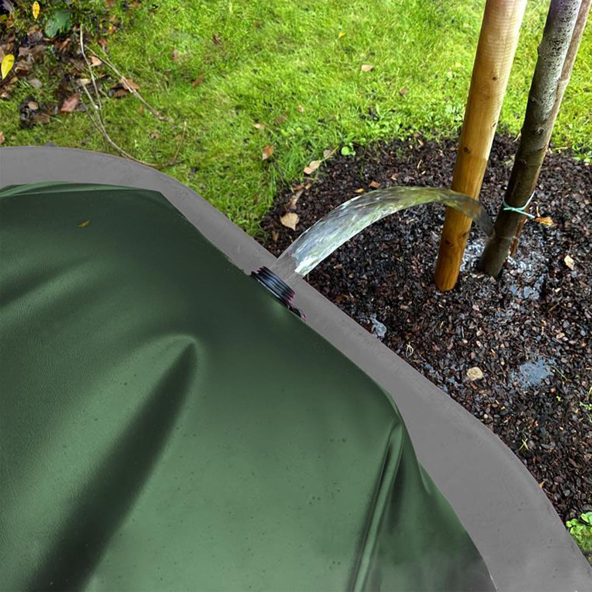 Gefüllter grüner FROGBAG ToGo Wasserbeutel mit Schraubverschluss auf einer schwarzen Antirutschmatte liegend.