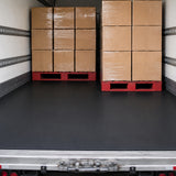 Schwarze SBR-Gummimatte als durchgehender Bodenbelag auf der Ladefläche eines LKW mit gestapelten Kartons auf Paletten.